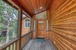 Step onto the inviting wooden porch of this charming cabin, featuring a beautiful natural wood exterior and a welcoming front door.