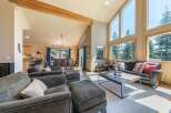 Experience breathtaking mountain views from this stunning living room, featuring a soaring vaulted ceiling with exposed wooden beams and expansive windows that flood the space with natural light.