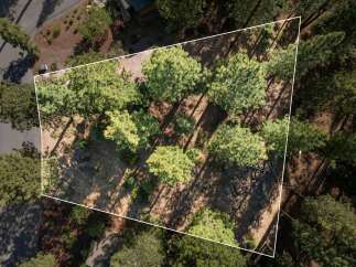 Discover this stunning aerial view of a wooded property, perfect for building your dream home.