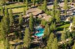 Experience luxury living with this stunning aerial view showcasing a resort-style swimming pool and hot tub nestled amidst lush pine trees.