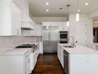 Experience luxury in this stunning modern kitchen, featuring sleek white cabinetry and a spacious island perfect for entertaining.