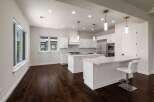 Experience modern luxury in this stunning white kitchen, featuring sleek cabinetry, a spacious island with seating, and top-of-the-line stainless steel appliances.