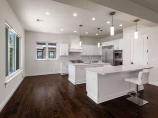 Experience modern luxury in this stunning white kitchen, featuring sleek cabinetry, a spacious island with seating, and top-of-the-line stainless steel appliances.