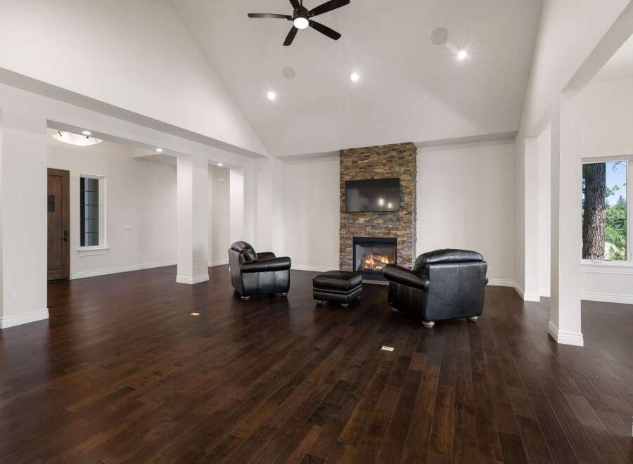 Experience luxury living in this spacious great room, featuring a stunning stone-clad fireplace and vaulted ceilings with recessed lighting.