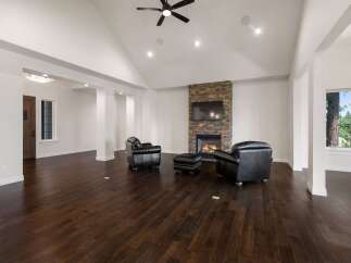 Experience luxury living in this spacious great room, featuring a stunning stone-clad fireplace and vaulted ceilings with recessed lighting.