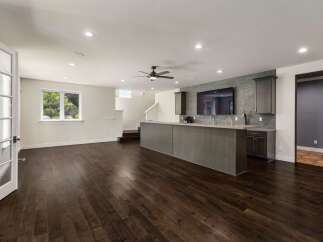 This spacious entertainment area features a modern wet bar with a sleek countertop and ample cabinet space, perfect for hosting guests.