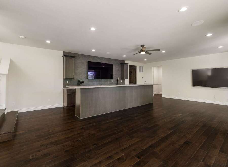 This modern basement features a sleek wet bar with a large island, perfect for entertaining guests.