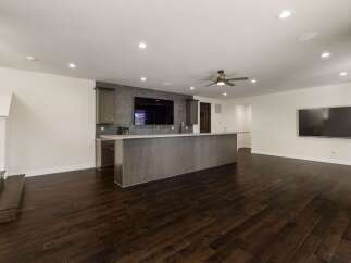 This modern basement features a sleek wet bar with a large island, perfect for entertaining guests.