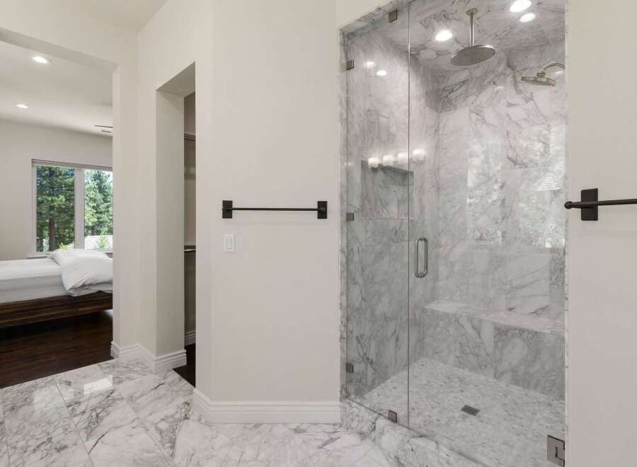 Experience luxury in this master suite featuring a spa-like marble bathroom with a spacious glass-enclosed shower.