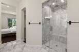 Experience luxury in this master suite featuring a spa-like marble bathroom with a spacious glass-enclosed shower.