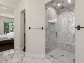 Experience luxury in this master suite featuring a spa-like marble bathroom with a spacious glass-enclosed shower.