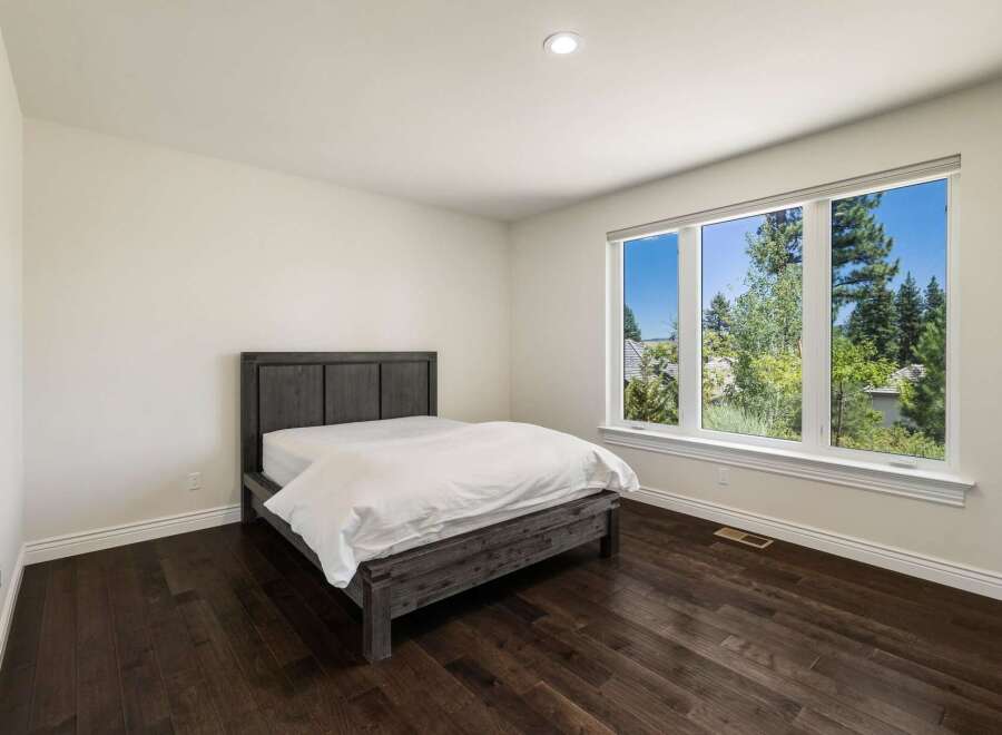 This bedroom features a modern dark wood bed frame with crisp white linens, creating a serene and inviting atmosphere.