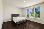 This bedroom features a modern dark wood bed frame with crisp white linens, creating a serene and inviting atmosphere.