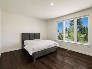This bedroom features a modern dark wood bed frame with crisp white linens, creating a serene and inviting atmosphere.