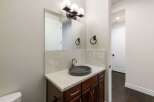 This modern bathroom features a sleek vanity with a dark vessel sink and a speckled quartz countertop.