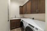 This laundry room boasts ample storage with dark wood cabinetry, both above and below the granite countertop.