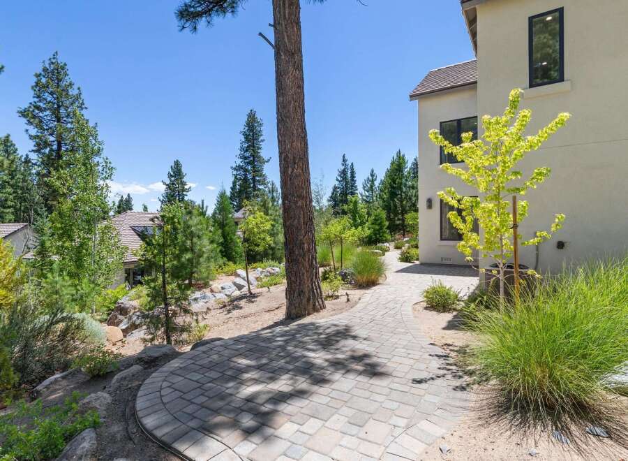 Discover this stunning property featuring a beautifully paved walkway leading through a lush, landscaped yard.