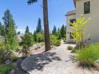 Discover this stunning property featuring a beautifully paved walkway leading through a lush, landscaped yard.
