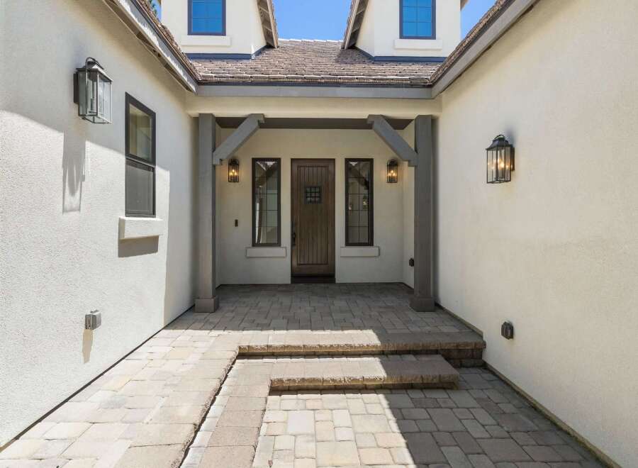 Step into this inviting entryway featuring a charming wooden door flanked by two elegant windows.