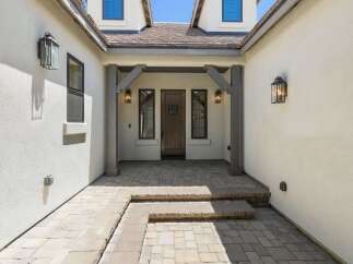 Step into this inviting entryway featuring a charming wooden door flanked by two elegant windows.