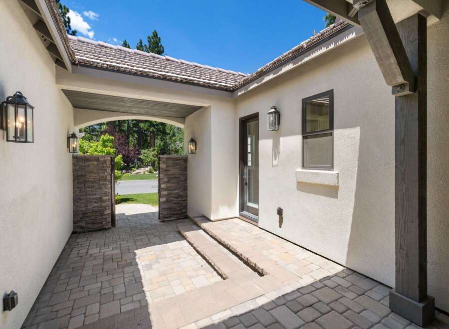 Step into this charming home through a welcoming courtyard featuring elegant stone pillars and a covered walkway.