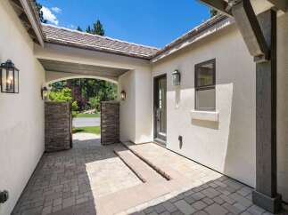 Step into this charming home through a welcoming courtyard featuring elegant stone pillars and a covered walkway.