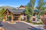 Experience luxury mountain living at this stunning property, featuring a grand entrance with stone accents and a welcoming wooden porte-cochère adorned with a festive wreath.