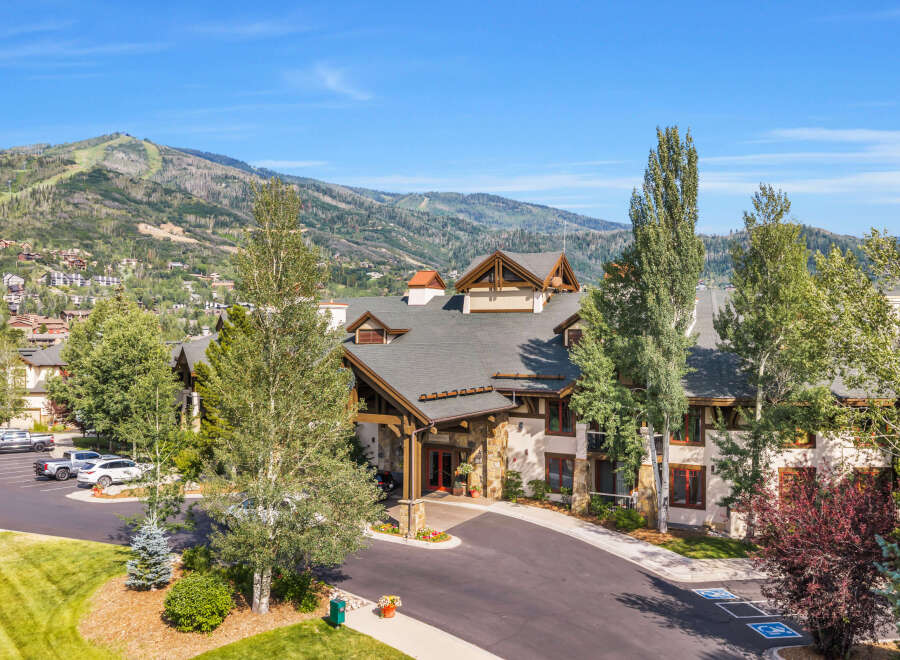 Experience luxury mountain living in this stunning property, featuring a grand entrance with stone accents and warm wood finishes.