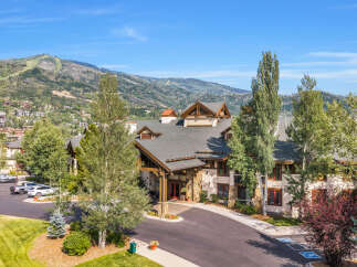Experience luxury mountain living in this stunning property, featuring a grand entrance with stone accents and warm wood finishes.