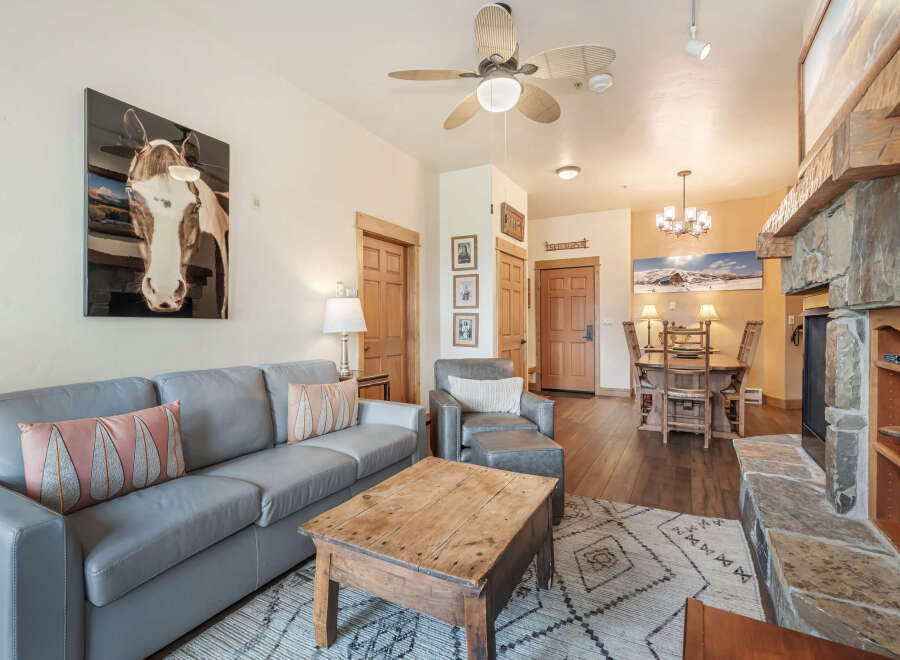 Experience rustic charm in this inviting living space, featuring a plush grey sofa adorned with decorative pillows and a rustic wooden coffee table.