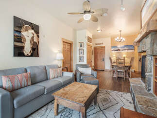 Experience rustic charm in this inviting living space, featuring a plush grey sofa adorned with decorative pillows and a rustic wooden coffee table.