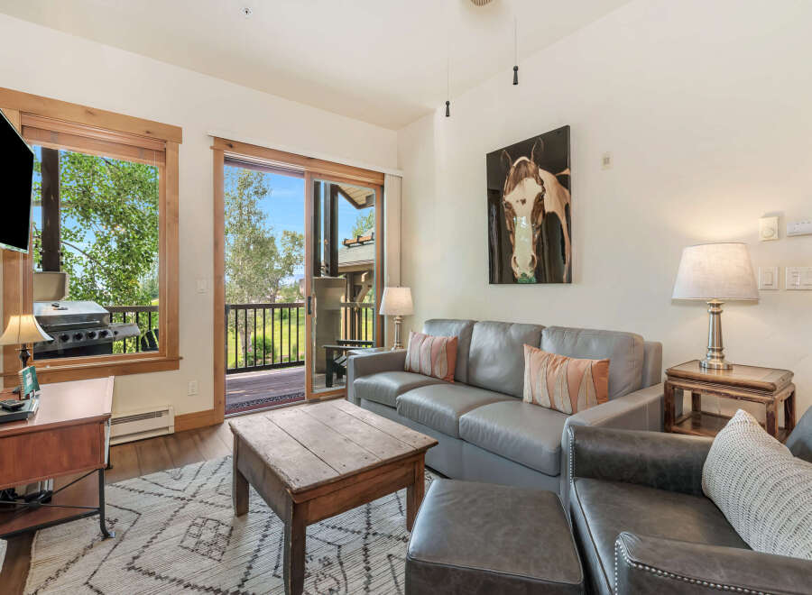 Experience comfortable living in this inviting living room, featuring a plush gray sofa and a rustic wooden coffee table perfect for gatherings.