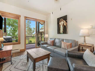 Experience comfortable living in this inviting living room, featuring a plush gray sofa and a rustic wooden coffee table perfect for gatherings.