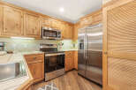 This charming kitchen features warm, natural wood cabinetry that complements the stainless steel appliances, including a side-by-side refrigerator and a built-in microwave.