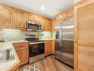 This charming kitchen features warm, natural wood cabinetry that complements the stainless steel appliances, including a side-by-side refrigerator and a built-in microwave.