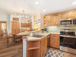 Experience cozy mountain living in this charming kitchen featuring warm wood cabinetry and a spacious granite-topped island perfect for casual dining.