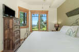 Experience breathtaking mountain views from this charming bedroom, featuring a comfortable king-size bed and a large dresser with a mounted TV.