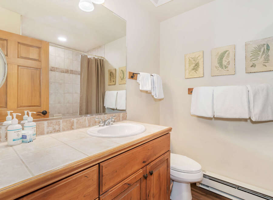 This charming bathroom features a spacious vanity with a tiled countertop and a white undermount sink, complemented by a wooden cabinet below.