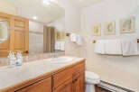 This charming bathroom features a spacious vanity with a tiled countertop and a white undermount sink, complemented by a wooden cabinet below.