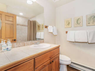 This charming bathroom features a spacious vanity with a tiled countertop and a white undermount sink, complemented by a wooden cabinet below.