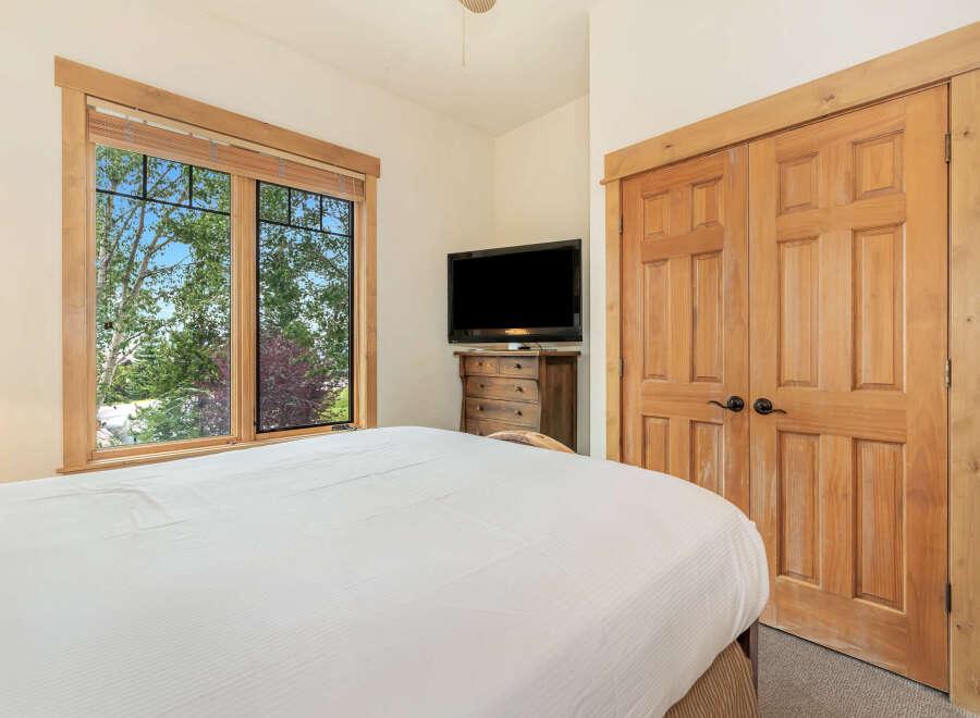 Experience comfort and style in this inviting bedroom, featuring a large window with scenic views and a convenient entertainment center.