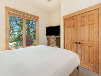 Experience comfort and style in this inviting bedroom, featuring a large window with scenic views and a convenient entertainment center.