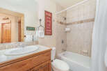 This charming bathroom features a spacious vanity with a white sink and chrome fixtures, complemented by a large mirror reflecting the wooden door and a decorative sign.