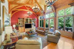 Experience luxurious living in this stunning great room, featuring a vaulted wood-beam ceiling and a vibrant red accent wall.