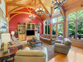Experience luxurious living in this stunning great room, featuring a vaulted wood-beam ceiling and a vibrant red accent wall.