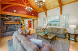 Experience rustic elegance in this spacious living room, featuring a grand stone fireplace and soaring vaulted ceilings with exposed wooden beams.
