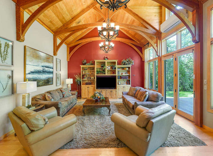 Experience rustic elegance in this stunning living room, featuring a soaring vaulted ceiling with exposed wooden beams and a dramatic chandelier.