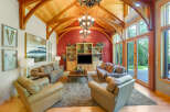 Experience rustic elegance in this stunning living room, featuring a soaring vaulted ceiling with exposed wooden beams and a dramatic chandelier.