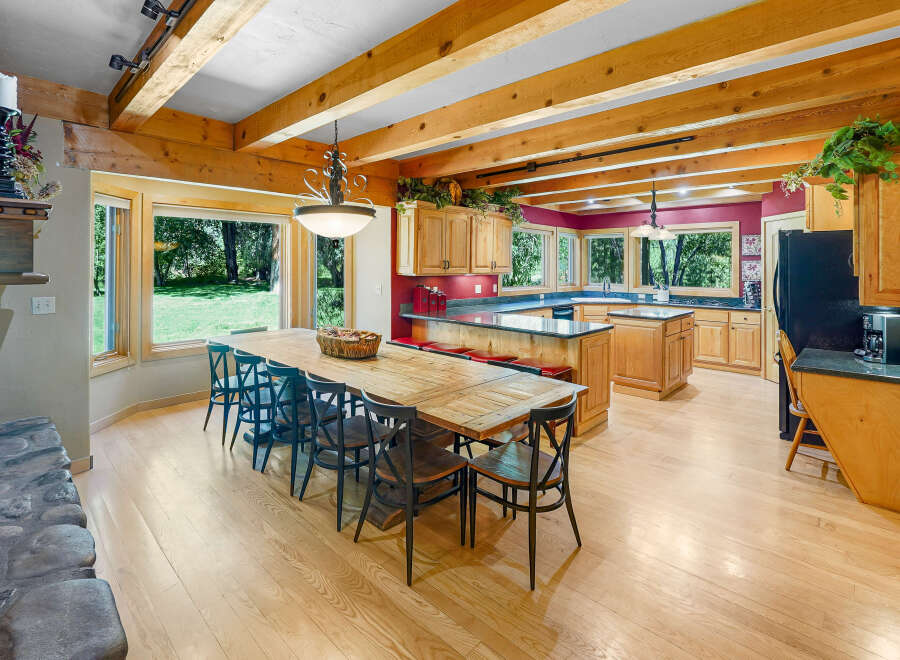 Experience rustic charm in this spacious kitchen and dining area, featuring exposed wooden beams and a large farmhouse table perfect for gatherings.