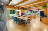 Experience rustic charm in this spacious kitchen and dining area, featuring exposed wooden beams and a large farmhouse table perfect for gatherings.